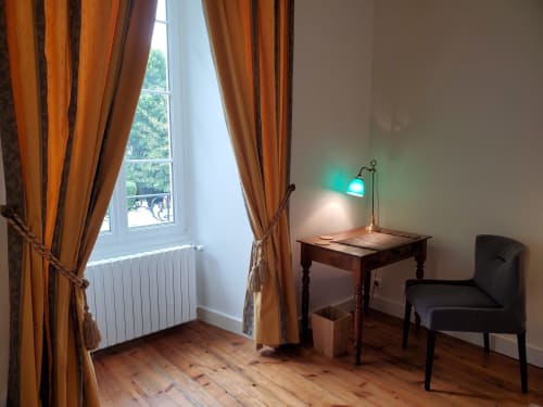 Chambre Verteuil avec vue sur le jardin au Logis des Tourelles, avec bureau, chaise, parquets et rideaux orange