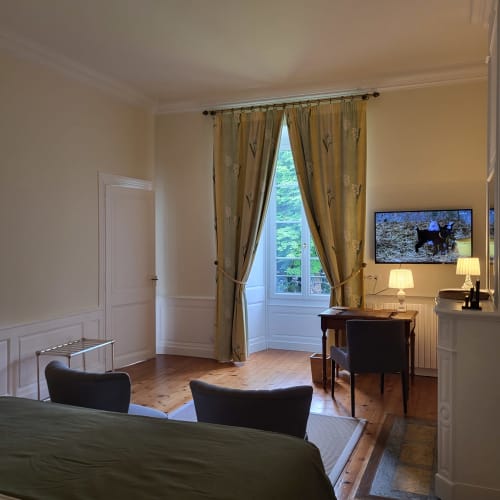 Chambre élégante du Logis des Tourelles avec espace de travail, rideaux dorés et parquet