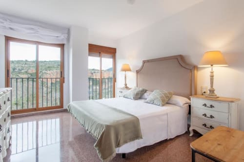 Dormitorio elegante en Rustikalpuente con vistas a las montañas, cabecero tapizado y balcón con vista al campo español
