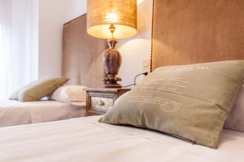 Acogedor dormitorio de hotel en Rustikalpuente con almohadas beige, lámpara de madera e iluminación cálida en España