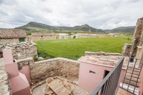 Patio de apartamentos Rustikalpuente con ruinas de piedra, estructuras modernas rosa y vistas al valle en España