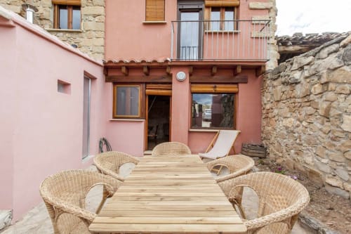 Patio del apartamento Rustikalpuente con asientos de mimbre, terraza de madera y muros de piedra en España