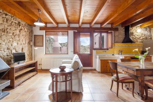 Interior rústico con vigas de madera, muros de piedra, cocina, comedor y vistas a la terraza en Rustikalpuente
