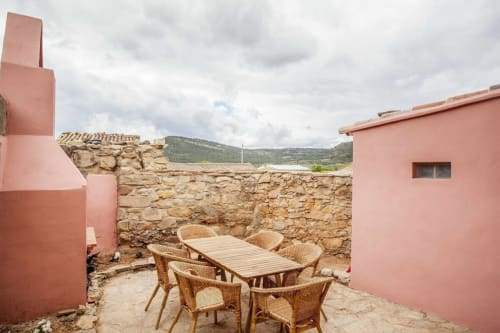 Patio rústico en Rustikalpuente con sillas de mimbre, mesa de comedor de madera, muros de piedra y vistas a las montañas en España