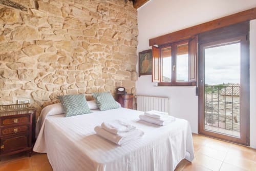 Habitación rústica de piedra con suelos de terracota, vigas de madera y balcón con vistas al campo en Rustikalpuente