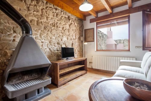 Apartamento Rustikalpuente con chimenea de piedra, vigas de madera, moderno módulo TV y zona de estar en blanco