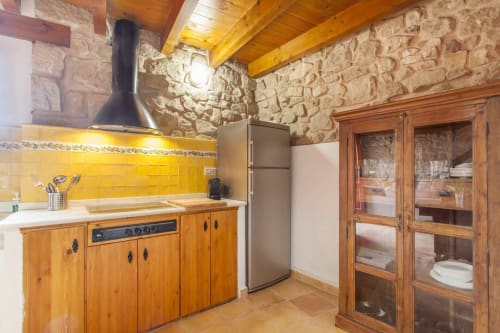 Cocina rústica en apartamento Rustikalpuente con muebles de madera, azulejos amarillos, electrodomésticos de acero inoxidable
