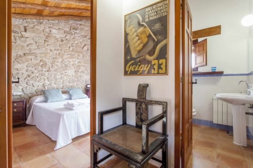 Apartamento Rustikalpuente con dormitorio de piedra, silla vintage y accesorios de baño modernos