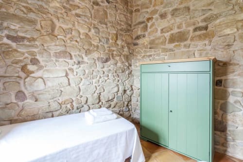 Dormitorio rústico de piedra con cama blanca y armario verde menta en apartamento Rustikalpuente, España