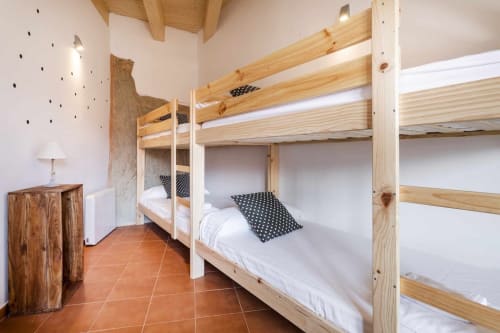 Literas de madera rústica con ropa de cama blanca en dormitorio luminoso del hotel Rustikalpuente