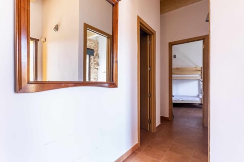 Pasillo del apartamento Rustikalpuente con espejo de marco de madera, azulejos de terracota y puertas abiertas hacia el dormitorio.