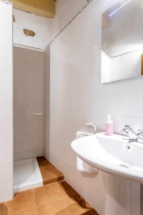 Baño moderno con paredes de azulejos blancos, lavamanos redondo, ducha a ras de suelo y piso de terracota en el apartamento Rustikalpuente, España