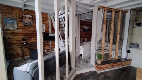 Les Troglos de Beaulieu rustic room with wooden walls, white pillars, garden view, and modern furnishings