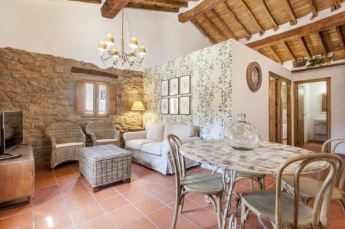 Apartamento rústico toscano con muros de piedra, piso de terracota, vigas de madera y cómoda sala de estar con mesa de comedor