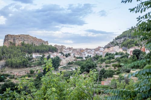 Pueblo pintoresco en la cima de una colina con edificios tradicionales, fortificaciones antiguas y exuberante paisaje mediterráneo en Rustikalpuente
