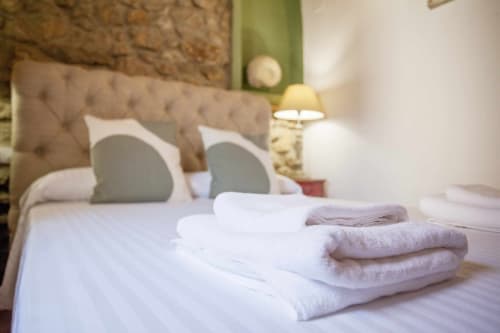 Dormitorio elegantemente diseñado en Rustikalpuente con toallas dobladas, cabecera capitonada e iluminación ambiental
