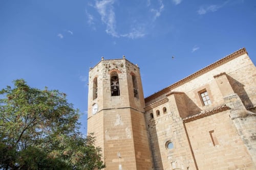 Iglesia de piedra histórica con campanario en Rustikalpuente, España bajo cielo azul despejado
