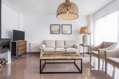 Salón rústico moderno en apartamento Rustikalpuente con sofá beige, mesa de café de madera, lámpara colgante tejida y