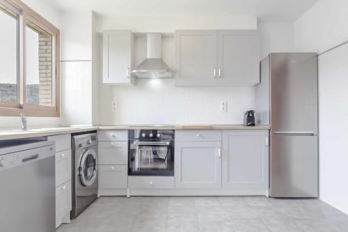 Cocina moderna de estilo blanco con electrodomésticos de acero inoxidable en el apartamento Rustikalpuente, España
