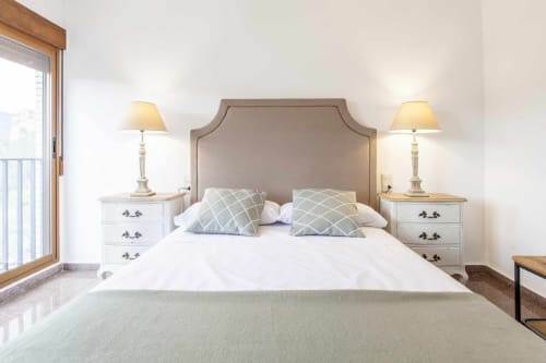 Dormitorio luminoso en apartamento Rustikalpuente con cabecera tapizada, mesillas blancas y lámparas juego