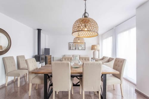 Comedor moderno en apartamento Rustikalpuente con lámpara colgante tejida, mesa de madera, sillas beige y chimenea