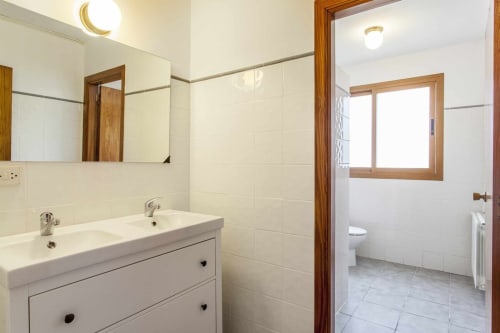 Baño moderno en apartamento Rustikalpuente con lavabo doble, azulejos blancos, espejo y puerta con marco de madera