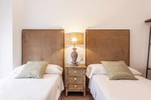 Camas gemelas con cabeceras tapizadas en marrón y almohadas decorativas en el apartamento Rustikalpuente en España