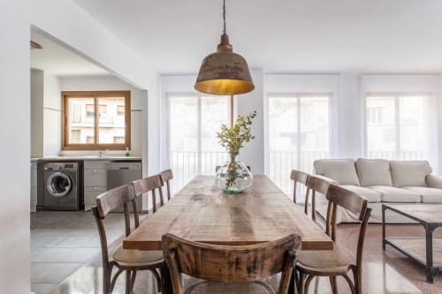 Zona de comedor del apartamento Rustikalpuente con mesa de madera, lámpara colgante vintage y vista a la cocina moderna en propiedad española