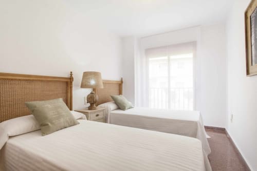 Habitación luminosa con camas individuales, cabeceros de ratán y luz natural en el apartamento Rustikalpuente, España