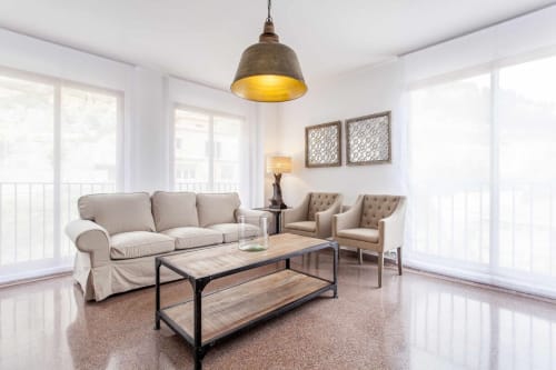 Moderno apartamento luminoso en Rustikalpuente con sofá beige, dos sillones decorativos, mesa de café industrial y lámpara colgante dorada