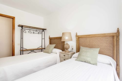Dormitorio doble con muebles de madera, cabeceros de ratán y cojines verdes en apartamento Rustikalpuente