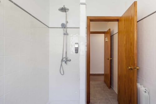 Baño moderno en apartamento Rustikalpuente con ducha abierta, azulejos blancos y marco de puerta de madera