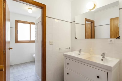 Baño moderno en apartamento Rustikalpuente con vanidorio de doble lavamano, acabados en madera y área de ducha en España