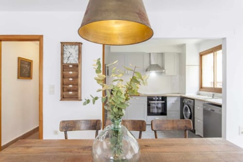 Comedor moderno con mesa de madera, lámpara colgante y cocina en el hotel Rustikalpuente, España