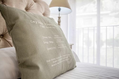 Cojín decorativo con marca de té negro de Ceilán en la cama del apartamento Rustikalpuente en España