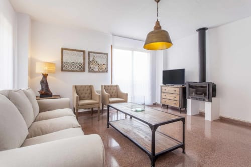 Sala moderna del apartamento Rustikalpuente con sofá beige, sillas de acento, lámpara colgante industrial y diseño contemporáneo