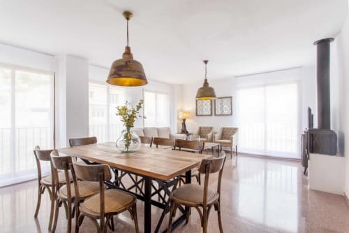 Comedor rústico moderno en apartamento Rustikalpuente con mesa de madera, lámparas colgantes doradas y área de descanso