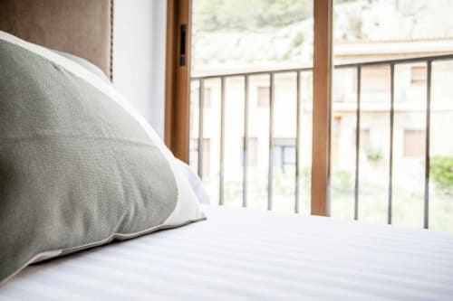 Acogedora habitación en apartamento Rustikalpuente con almohada gris, ropa de cama blanca y balcón con vistas al patio español