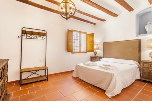 Dormitorio del apartamento Rustikalpuente con vigas de madera, baldosas de terracota y decoración tradicional española