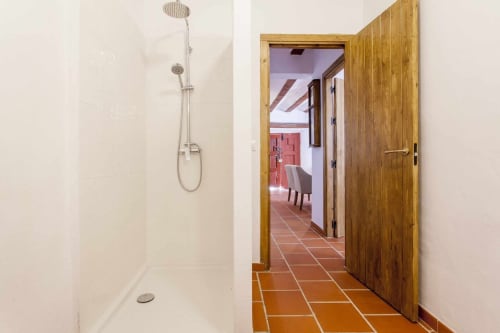Baño moderno con ducha de lluvia y puerta de entrada de madera en el apartamento Rustikalpuente, España