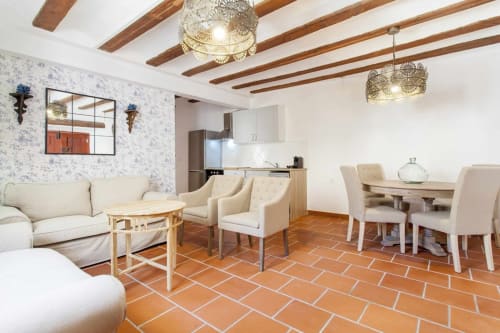 Sala de estar del apartamento Rustikalpuente con muebles color crema, piso de baldosa terracota, vigas de madera y cocina moderna en España
