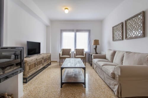 Luminoso salón moderno en apartamento Rustikalpuente con sofá beige, chimenea y decoración contemporánea en España