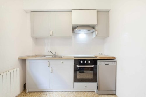 Cocina moderna en apartamento Rustikalpuente con muebles blancos, horno integrado, lavavajillas y encimeras de madera