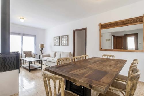 Espacioso apartamento en Rustikalpuente con mesa de comedor, sofá crema, sillas de madera, chimenea y espejo ornamentado en la sala