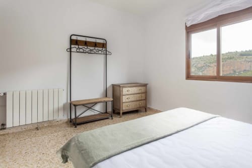 Dormitorio rústico en Rustikalpuente con cama, perchero de metal, cómoda de madera y vista a las montañas desde la ventana