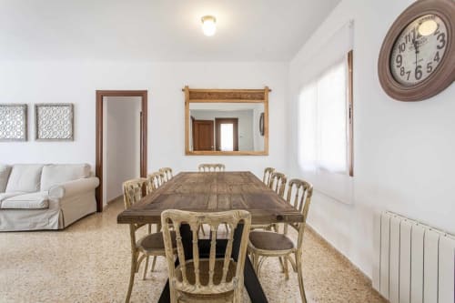 Comedor del apartamento Rustikalpuente con mesa de madera, sillas de mimbre, sofá beige y decoración rústica
