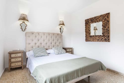 Dormitorio rústico en Rustikalpuente con cabecero capitonado, mesitas de madera y espejo decorativo