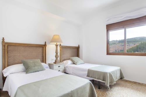 Luminosa habitación doble en Rustikalpuente con cabeceros de ratán, ropa de cama blanca y vistas a la montaña
