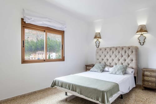 Luminoso dormitorio en Rustikalpuente con cabecero capitonado, ventanas de madera con vistas al bosque, ropa de cama blanca