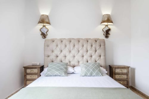 Elegante dormitorio en apartamento Rustikalpuente con cabecera acolchada, mesitas de noche gemelas y apliques decorativos